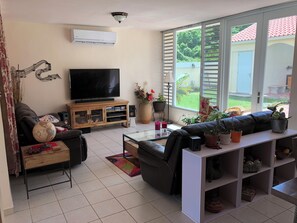 A living room with a flat-screen TV, leather sofa, coffee table, and potted plants. - A Private Paradise by the Rainforest in Sunny Luquillo (Pitahaya)