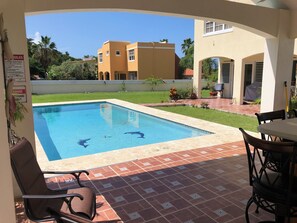 A swimming pool with clear blue water, surrounded by a patio area with tiled flooring and outdoor furniture. - A Private Paradise by the Rainforest in Sunny Luquillo (Pitahaya)