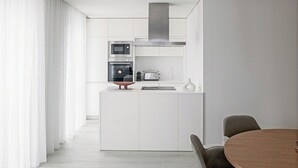 Eine moderne Küche mit weißen Schränken, einem eingebauten Ofen, einer Mikrowelle und einer kleinen Kochinsel mit einem Toaster.