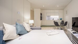 Een moderne hotelkamer met een bed, een bureau, een stoel, een televisie en een kitchenette.