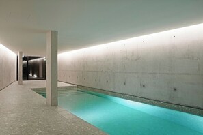 A modern indoor swimming pool with a concrete floor and walls, and a clear blue pool. - T1 Exclusive Garden and Pool na Ribeira (Vila Nova de Gaia)