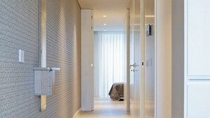 A modern hallway with a brick wall, a door with a curtain, and a bench. - Porto Glam River View and Spa (Vila Nova de Gaia)
