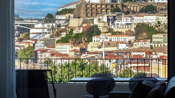 A balcony with a view of a historic building with a dome and arches, surrounded by residential buildings. - Porto Glam River View and Spa (Vila Nova de Gaia)