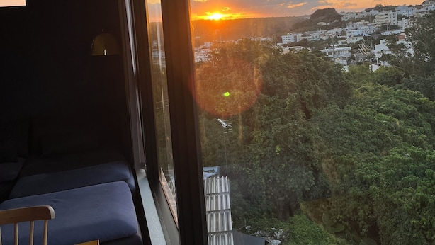Una habitación con un ventanal grande que da a un paisaje urbano al atardecer.