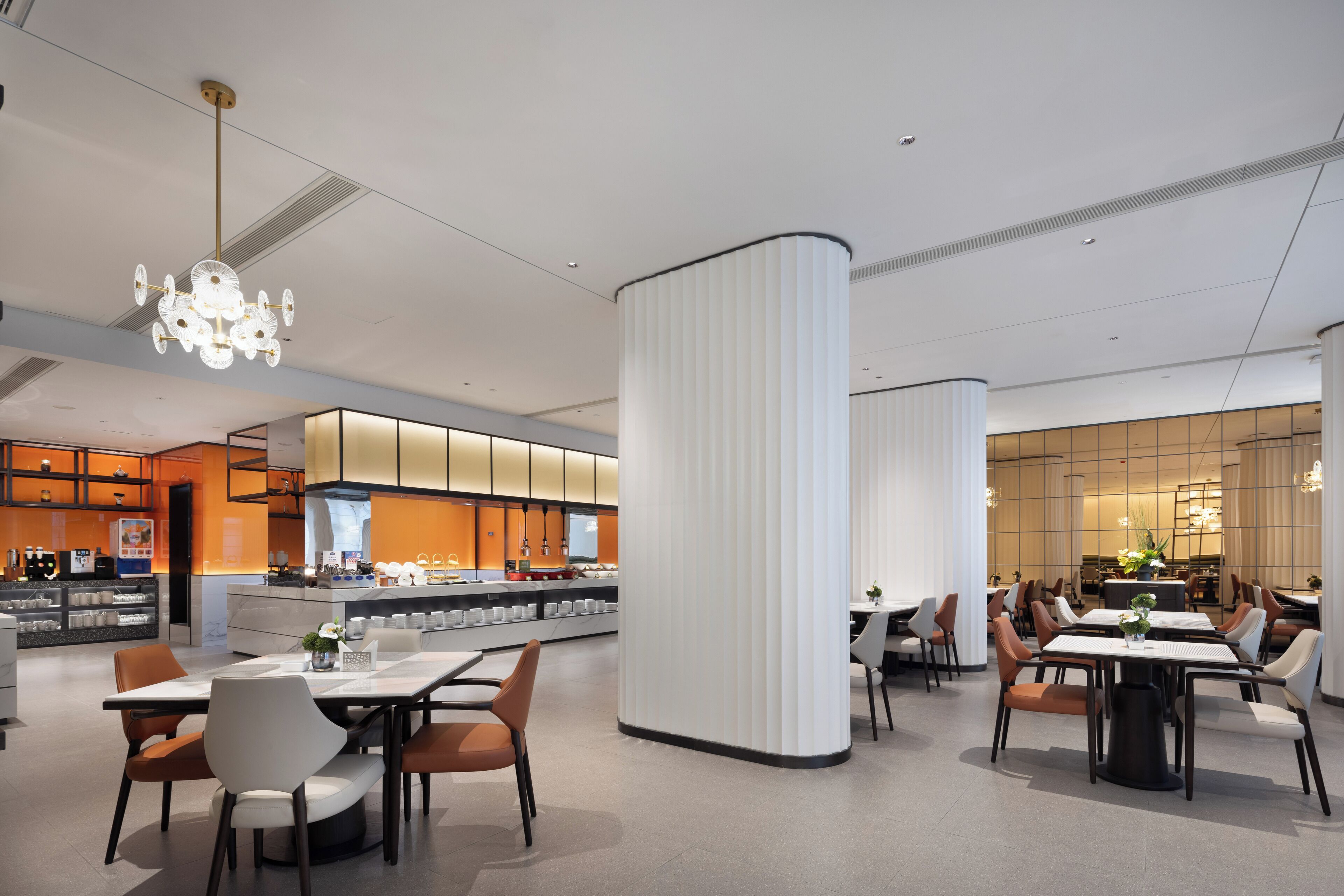 Un restaurante moderno con barra central, techos altos y decoración contemporánea.