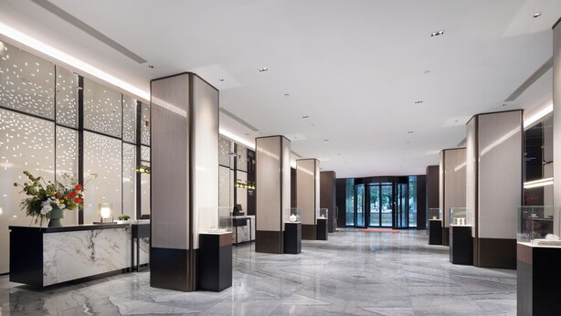 Un hall d’entrée moderne avec un sol en marbre, un comptoir d’accueil et des vitrines en verre.