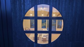 A circular window with a view of a room featuring a sofa, a table, and a chair.