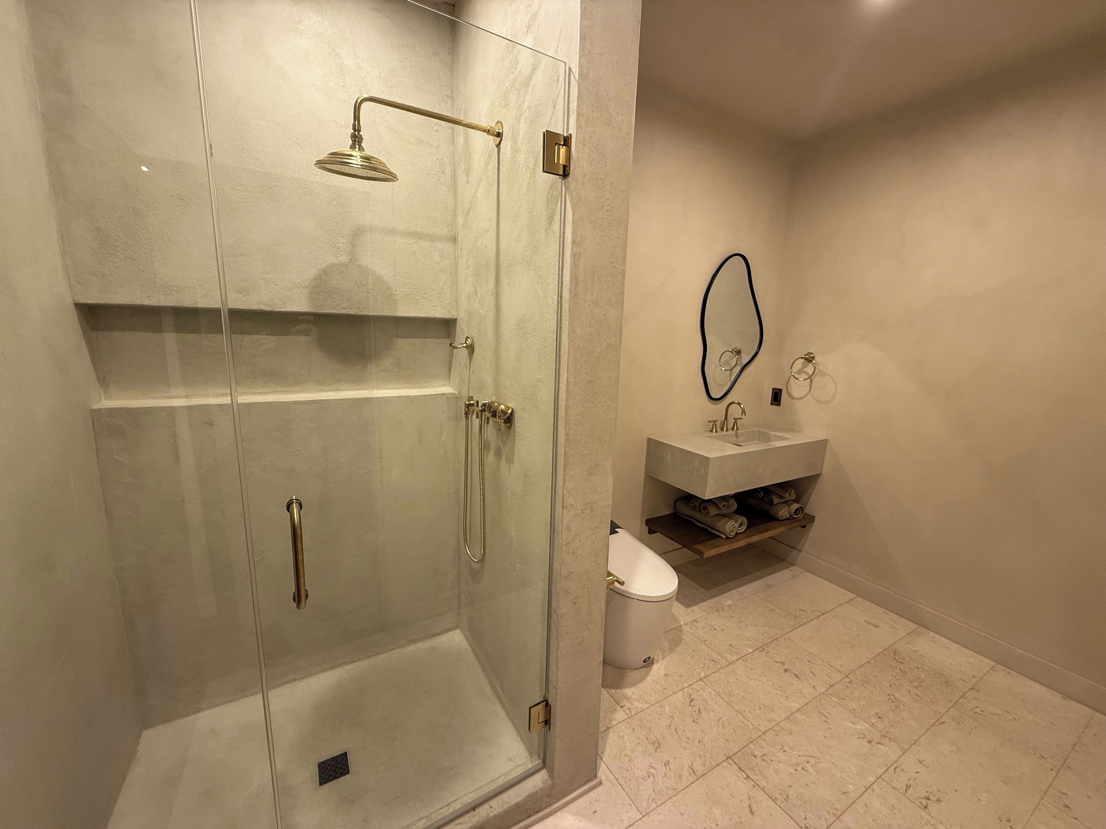 A bathroom with a glass-enclosed shower, a sink with a mirror, and a toilet.