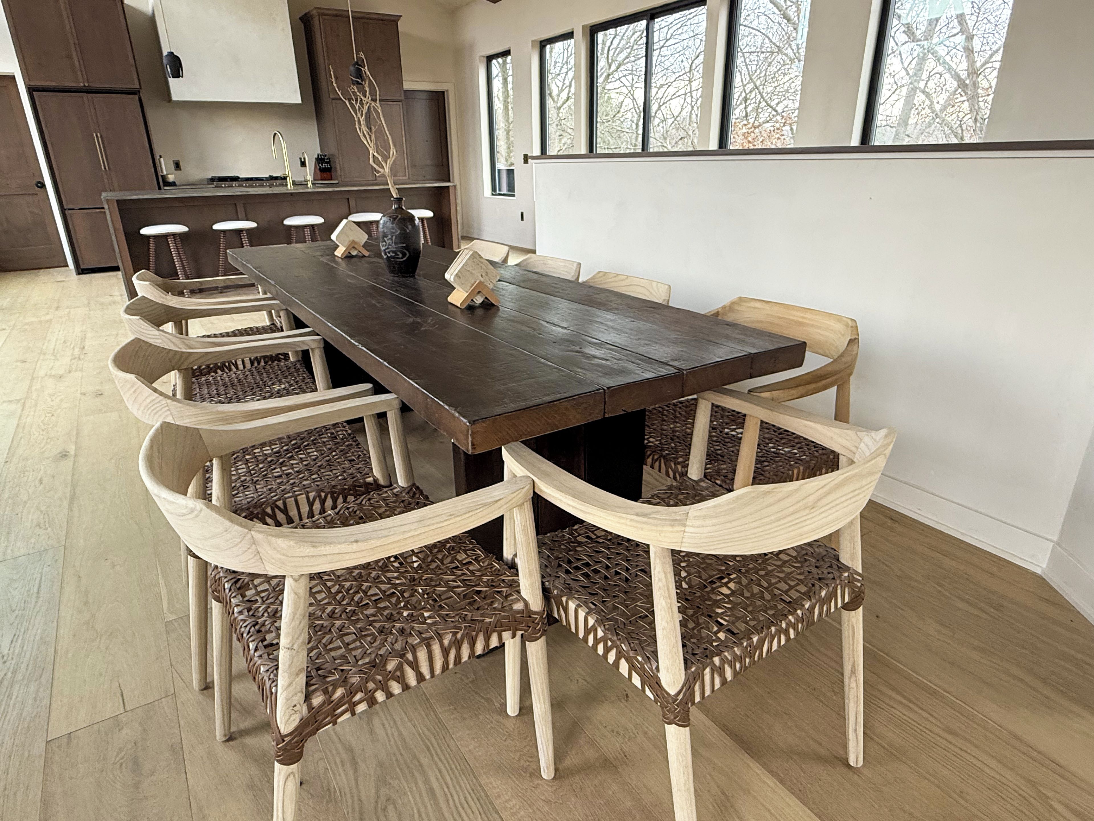 A dining area with a long wooden table and six woven chairs.
