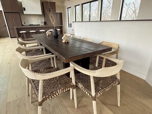 Comedor con una larga mesa de madera y seis sillas tejidas.