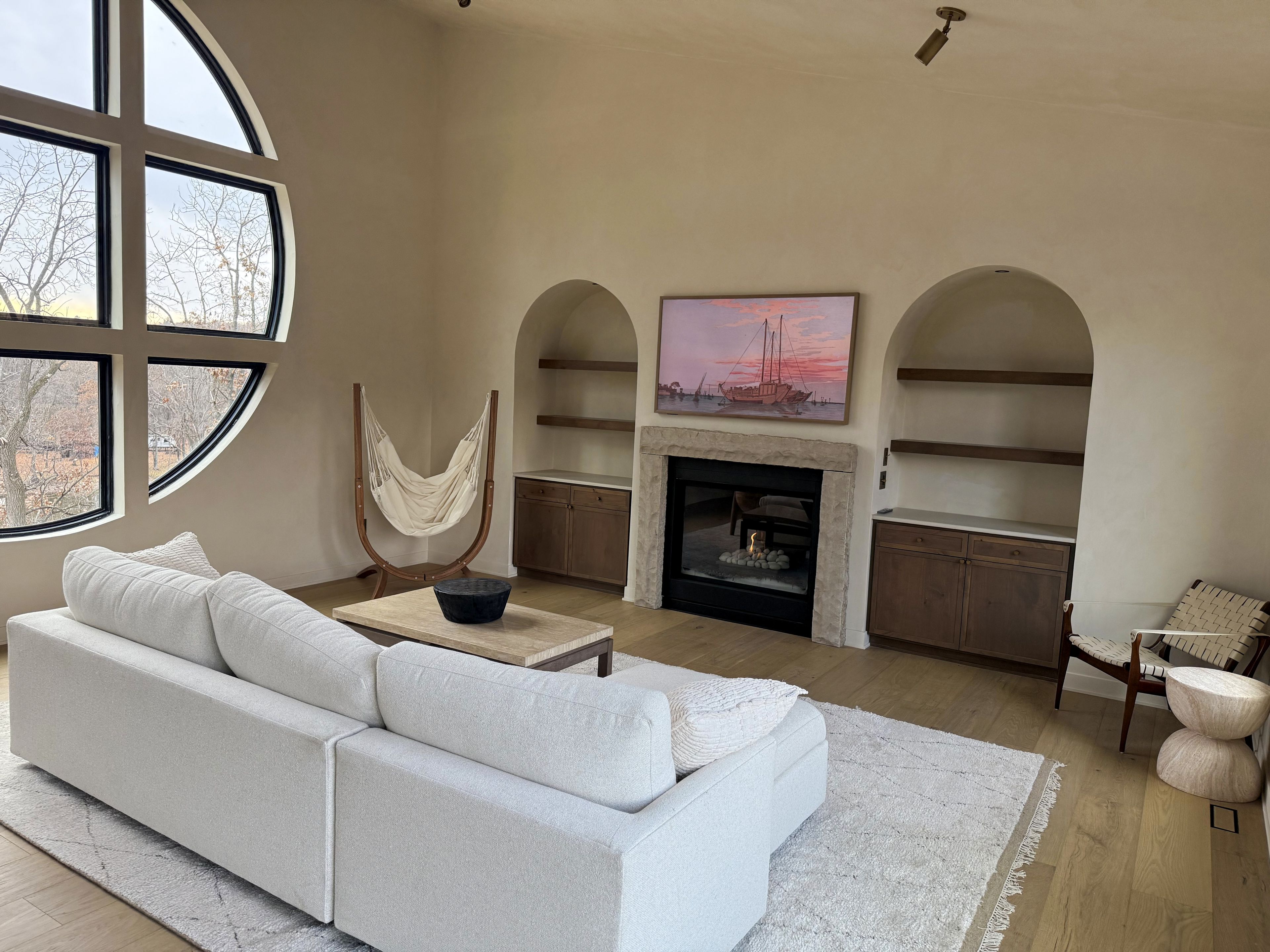 A living room with a white sofa, a fireplace, and a large window.