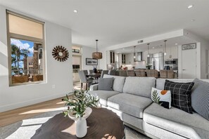Ein modernes Wohnzimmer mit grauem Sofa, Couchtisch und großem Fenster.