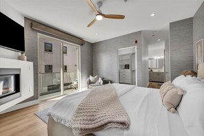 Een moderne slaapkamer met een groot bed, een open haard en een schuifdeur naar een balkon.