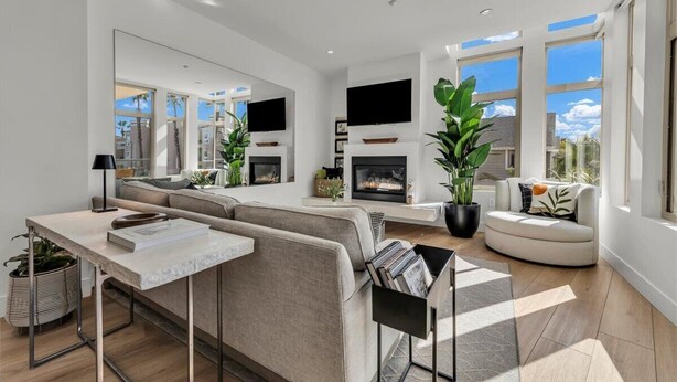 A modern living room with a fireplace, large windows, and a seating area. - Relaxed Coastal Vibes - Luxury Accomodations & Steps to the Sand, Shops and Pier (Oceanside)