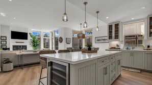 A spacious kitchen with a large island, pendant lighting, and a view to the outside. - Relaxed Coastal Vibes - Luxury Accomodations & Steps to the Sand, Shops and Pier (Oceanside)