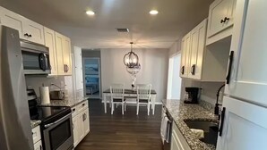 A modern kitchen with white cabinets, stainless steel appliances, and a dining area with a chandelier. - Escape to "Warm Mineral Springs"a Place Where You Can Relax And Heal your body. (North Port)