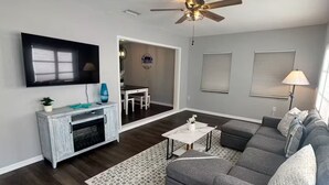 A modern living room with a gray sectional sofa, a white coffee table, and a ceiling fan. - Escape to "Warm Mineral Springs"a Place Where You Can Relax And Heal your body. (North Port)