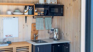 A compact kitchen with a microwave, toaster, and coffee maker on a wooden wall. - Thomson's Nook - Taupo (Taupo)