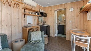 A cozy room with a sofa, a small table, a microwave, and a sink. - Thomson's Nook - Taupo (Taupo)