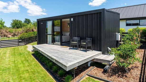 A modern house with a deck, a sliding glass door leading to a patio, and a small garden area. - Thomson's Nook - Taupo (Taupo)