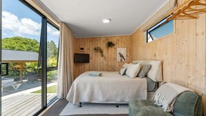 A bedroom with a large window, a bed, a sofa, and a TV. - Thomson's Nook - Taupo (Taupo)