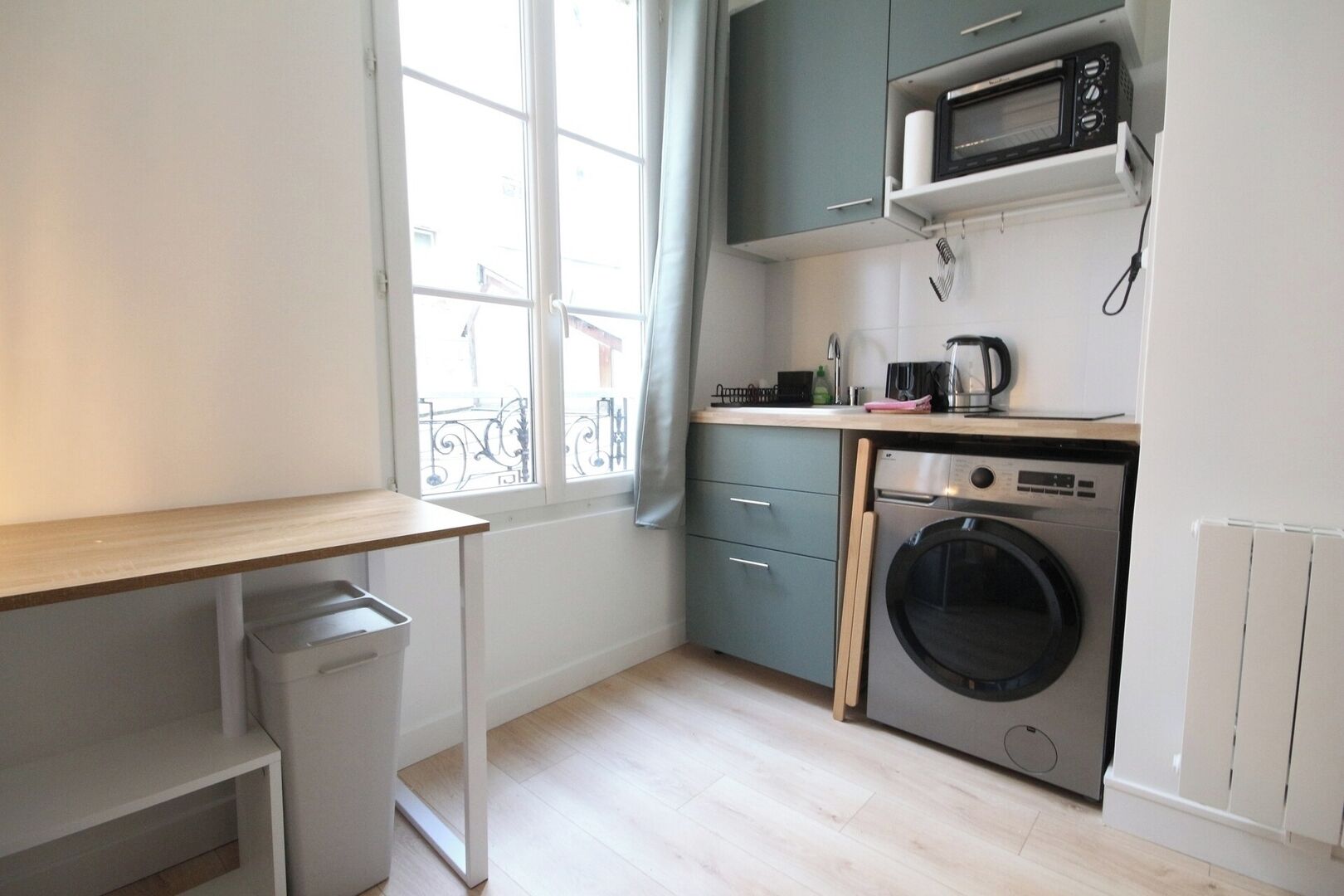 A compact kitchen with a washing machine, a microwave, and a small countertop.