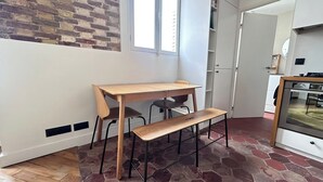 Eine kleine, moderne Küche mit Einbauofen und einem Essbereich mit Holztisch und zwei Stühlen.