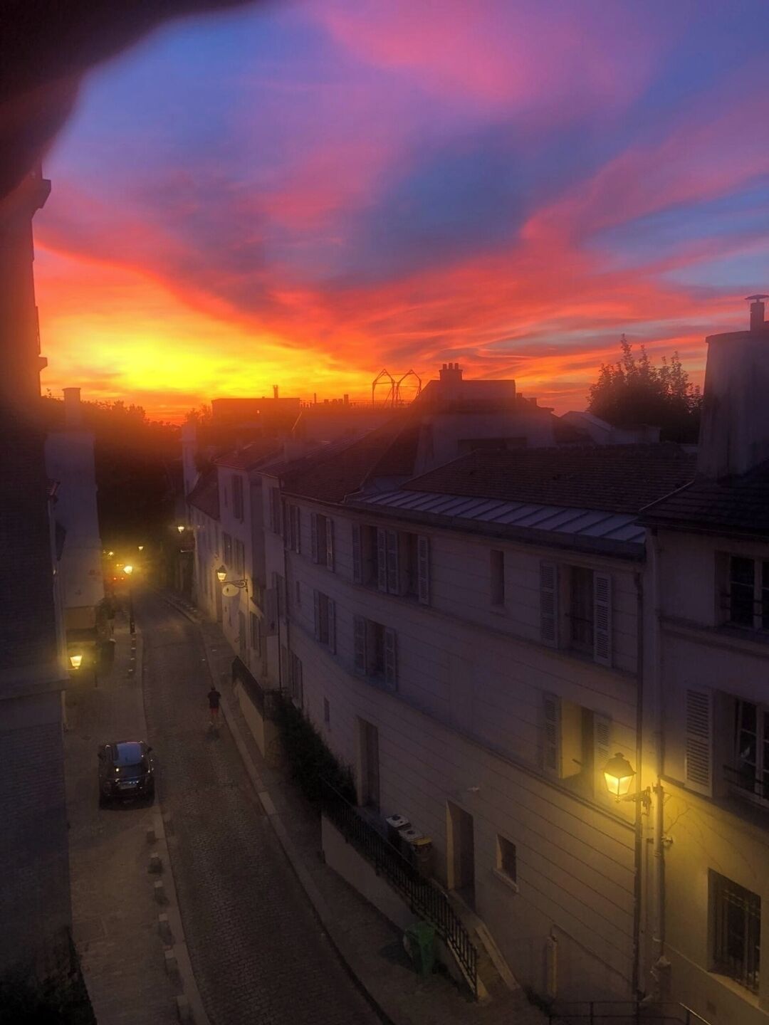 Straatbeeld bij zonsondergang met gebouwen en lantaarns.