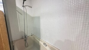 Een badkamer met witte betegelde wanden en een bad.