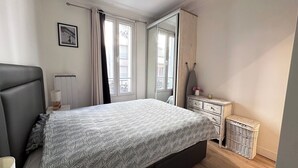 Une chambre à coucher avec un lit, une commode, un miroir et une fenêtre.