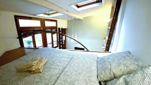A bedroom with a bed, a skylight, and a view of the outside balcony. - Loft - Montmartre / Moulin Rouge / Pigalle (Paris)