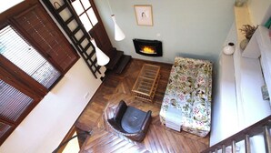 A living room with a fireplace, a sofa, a chair, and a wooden floor. - Loft - Montmartre / Moulin Rouge / Pigalle (Paris)