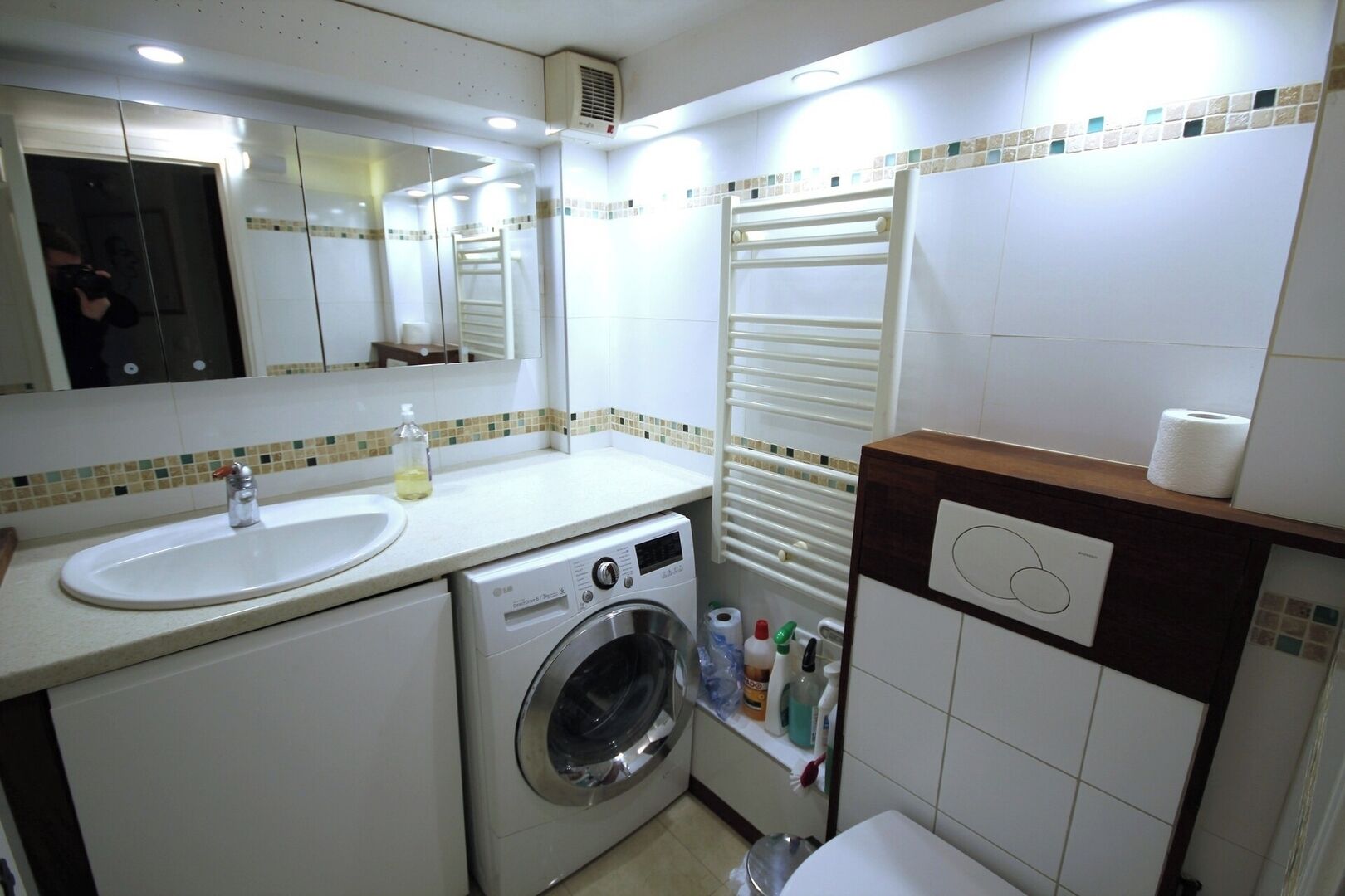 Une petite salle de bain d’hôtel comprenant un lavabo, un lave-linge et des toilettes.