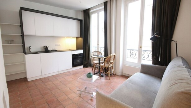 Un espacio habitable compacto con kitchenette, comedor y balcón.