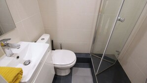 Un baño con lavamanos blanco, inodoro y cabina de ducha de vidrio.