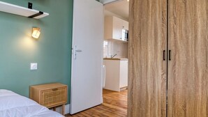 A bedroom with a large bed, a wardrobe, and a kitchenette in the background. - On Room Last Floor - Batignolles (Paris)