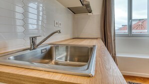 A modern kitchen with a stainless steel sink, wooden countertop, and white hexagonal tiles. - On Room Last Floor - Batignolles (Paris)
