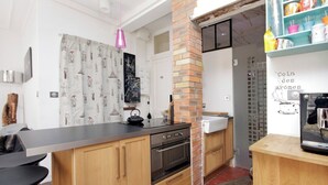Una cocina moderna con un pilar de ladrillo, electrodomésticos de acero inoxidable y una isla de madera.