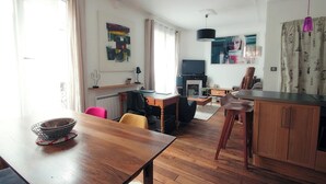 Una sala de estar moderna con una mesa de comedor de madera, un televisor y una chimenea.