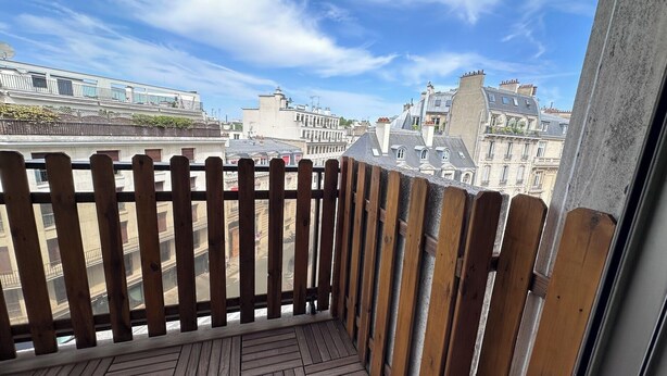 A wooden balcony with a view of historic buildings. - Studio balcony and fiber – Parc Monceau 8th (Paris)