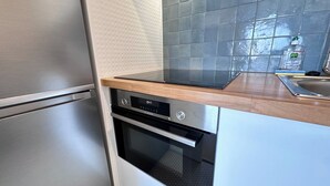 A kitchen with stainless steel appliances, a wooden countertop, and a tiled backsplash. - Studio balcony and fiber – Parc Monceau 8th (Paris)