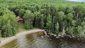 Una cabaña rodeada de un bosque tupido y un lago.