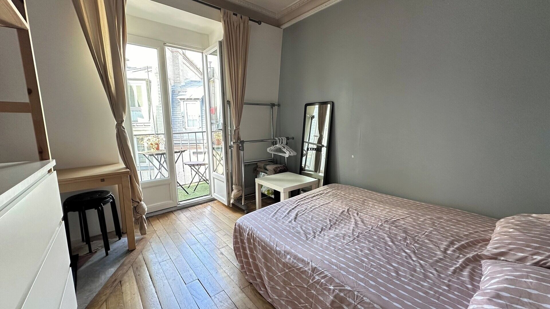 A bedroom with a bed, a desk, a chair, and a window with curtains.
