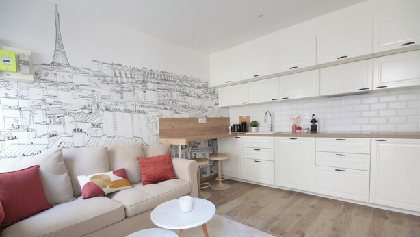 Um apartamento moderno com uma cozinha compacta, um sofá com almofadas e uma mesa de centro.