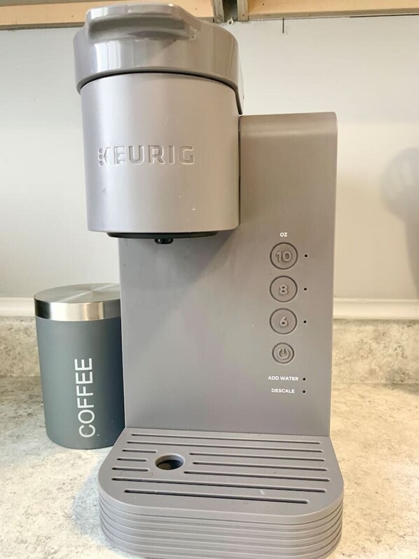 Une machine à café Keurig, avec une tasse à café placée à côté.