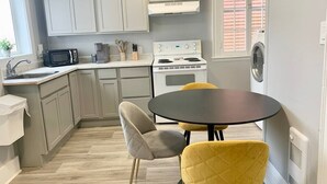 A modern kitchen with white cabinets, a stove, a microwave, and a table with two chairs. - Cozy 1BR by Hospital & Uptown (Saint John)