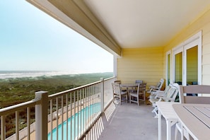 Ein Balkon mit Blick auf das Meer, ein Pool und einige Stühle und Tische.