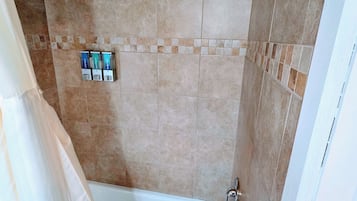 Une salle de bain avec une baignoire, une douche et des murs carrelés.