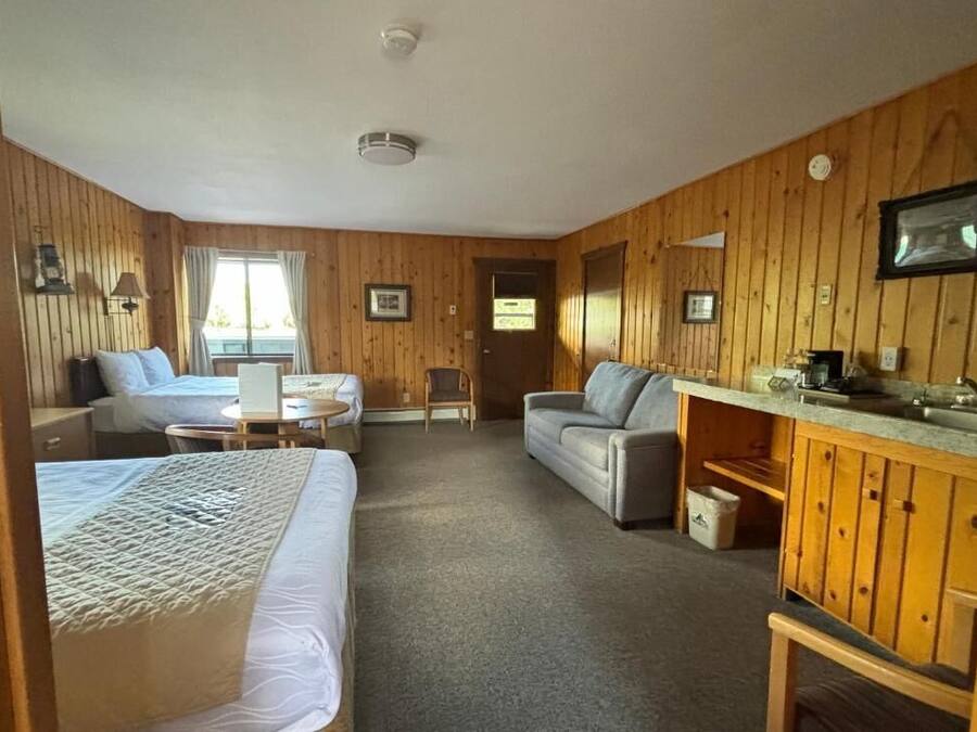 A cozy room with two beds, a sofa, a small table, and a kitchenette.