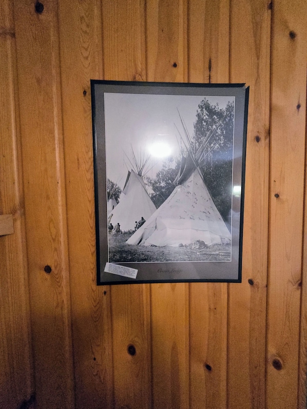A framed black and white photograph of two snow-covered teepees on a wooden wall. - Alpine Lodge (Red Lodge)
